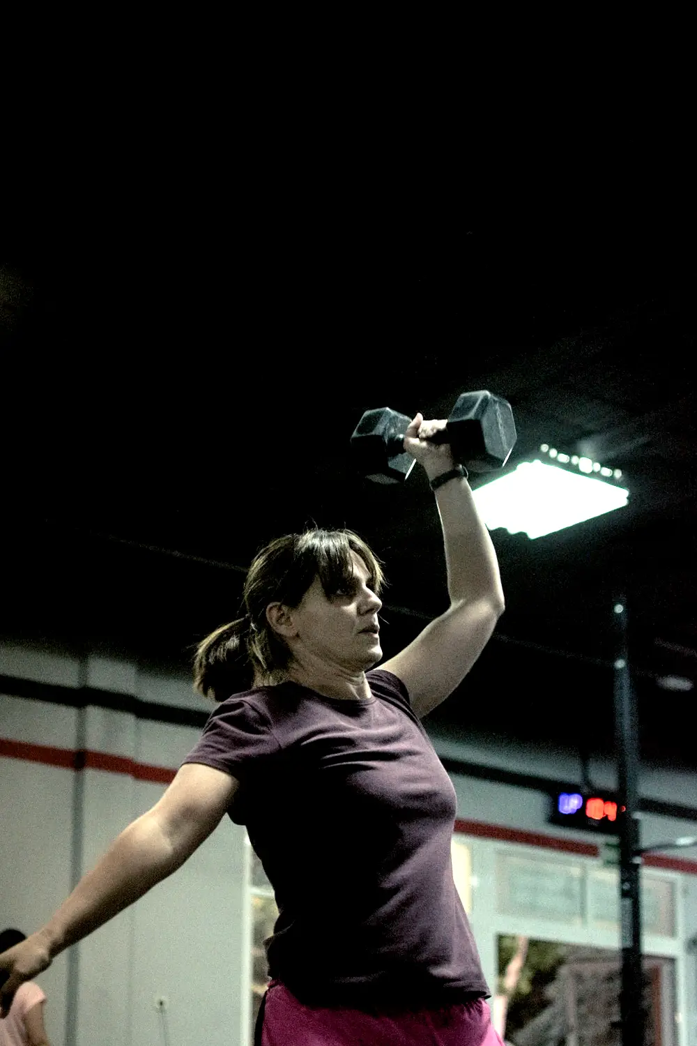 Atleta con mancuerna sobre la cabeza en un WOD de CrossFit